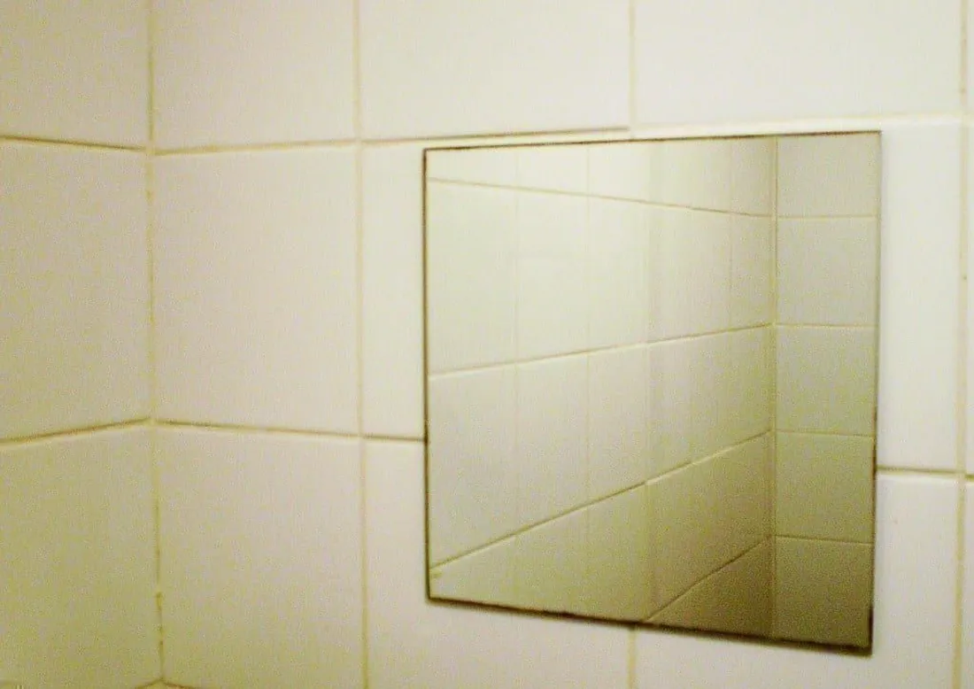 Geflieste Wand mit Waschbereich und Spiegel