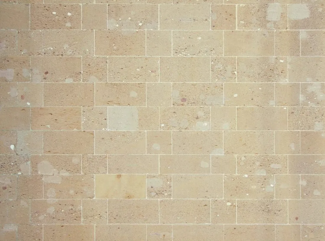 Beige Natursteinfläche mit typischer, warmer Travertin-Struktur