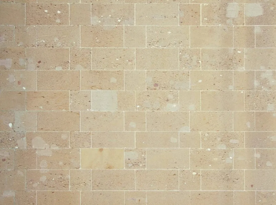 Beige Natursteinfläche mit typischer, warmer Travertin-Struktur